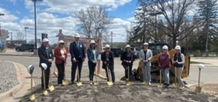 People wearing hard hats hold shovels on newly graded land.