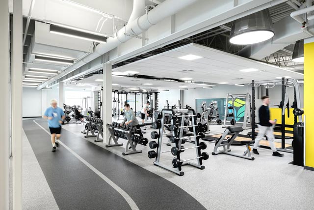 weights in the middle of a room and a man running around a track that goes around the perimeter
