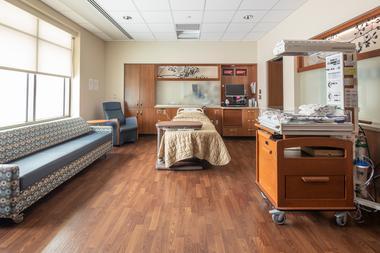A clean and spacious hospital room with bith, sofa, and clean and modern medical supplies.