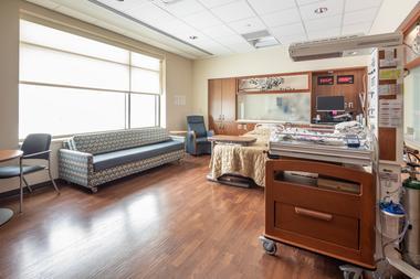 A clean and spacious hospital room with bith, sofa, and clean and modern medical supplies